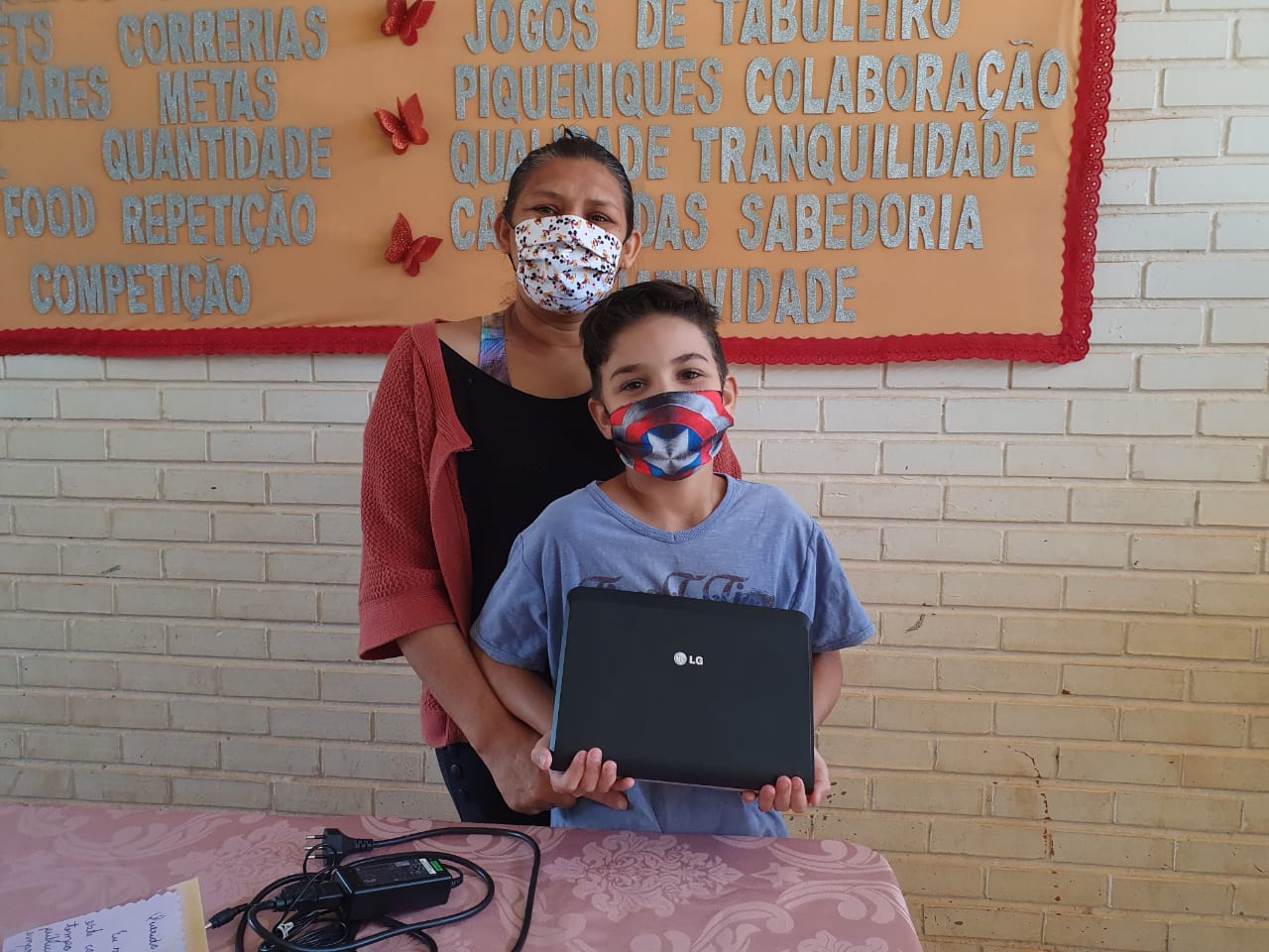 Mãe e filho segurando aparelho de notebook que receberam como doação