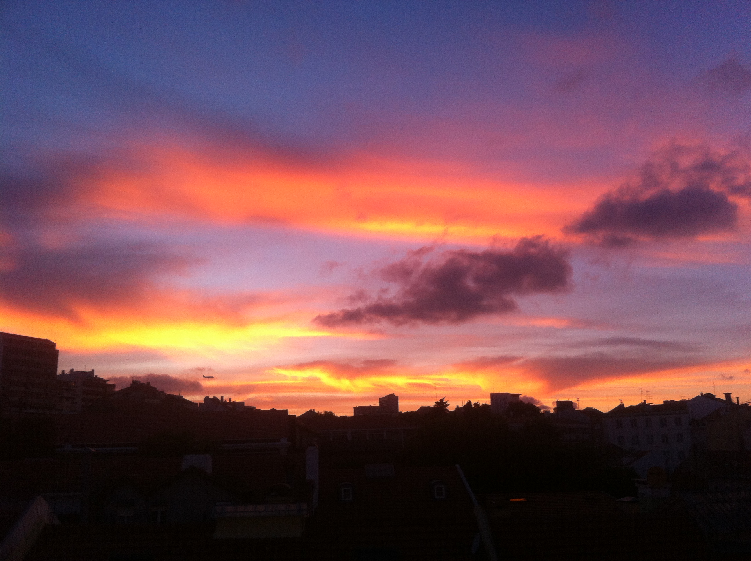 Foto de um pôr do sol em Lisboa, onde o céu fica multicolorido em tons fortes e vibrantes